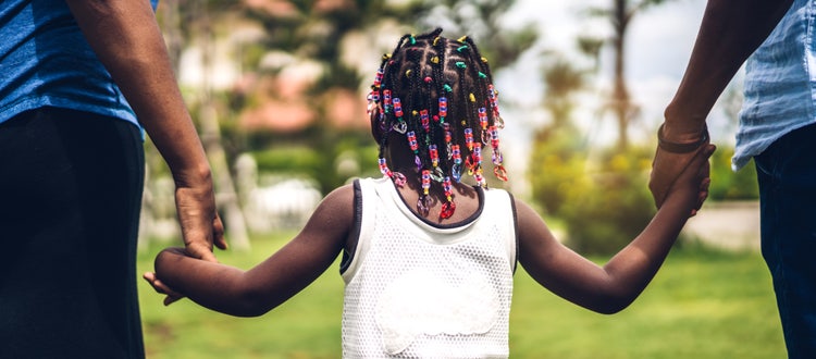 a family with their backs facing the camera holding hands