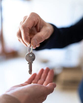 a hand extending a set of keys into another hand
