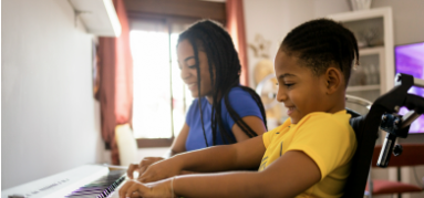 a smiling child in a wheelchair playing the piano