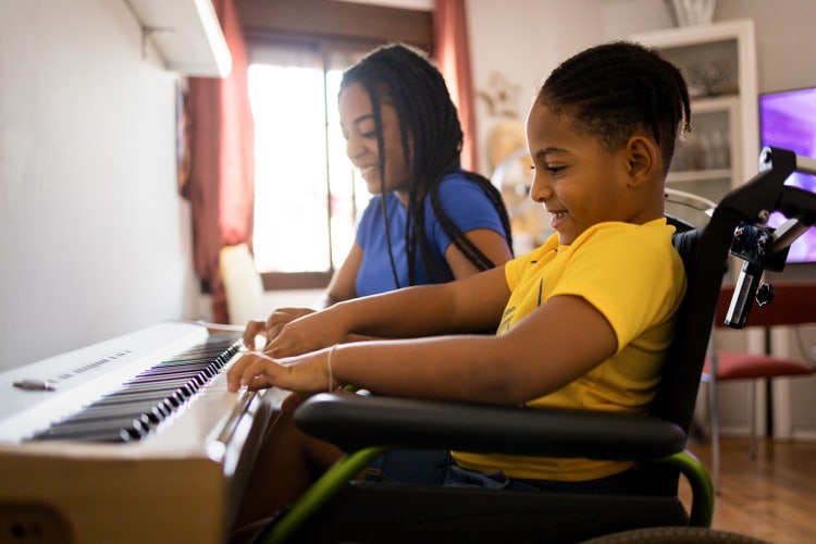 a smiling child in a wheelchair playing the piano