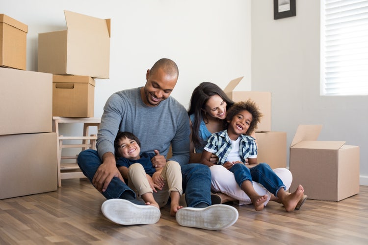a family sitting on the floor after moving into their first house